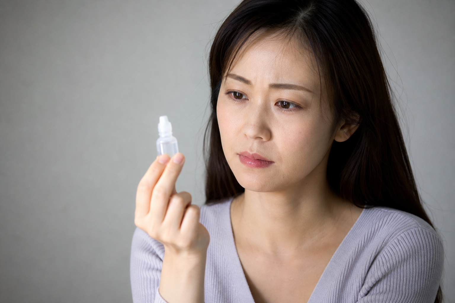 目の不調を心配して目薬を手に取る女性